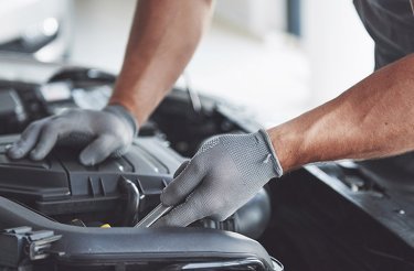 man in automotive segment fixing something on a car engine
