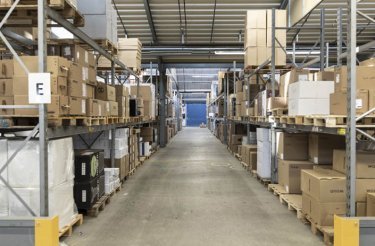 A look down a warehouse aisle with full shelves in the logistics segment