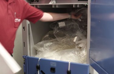 Man placing plastic into a baler while following safety tips for use