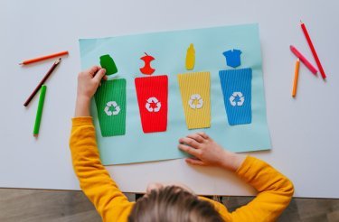 little-girl-in-yellow-shirt-looking-at-clipboard-of-waste-sorting-solutions