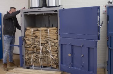 Man performing cardboard disposal by bailing out a baler