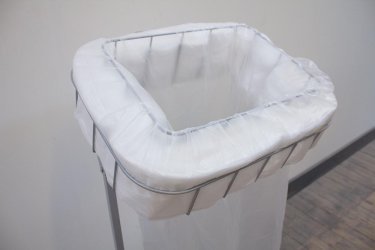 White plastic waste bag opened on a floor stand